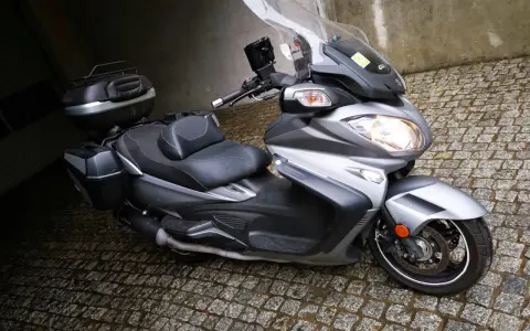 Srebrny Suzuki Burgman 650 z kuframi, gotowy do podróży. Czy są jakieś wady?