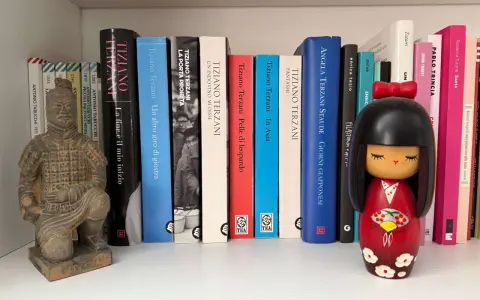 Statua guerriero terracotta e una collezione di libri di Tiziano Terzani, tra cui "La fine è il mio inizio" e "Un altro giro di giostra".