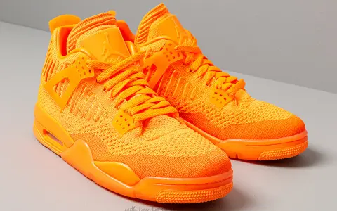 Un paio di scarpe Jordan 4 arancioni brillanti, con tomaia in maglia e dettagli iconici.