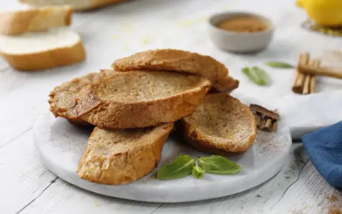 Torrijas al horno doradas y crujientes, espolvoreadas con canela, listas para disfrutar.