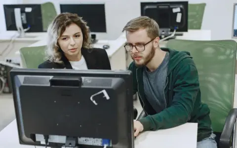 Kobieta i mężczyzna analizują dane na monitorze, dbając o zapewnienie jakości.