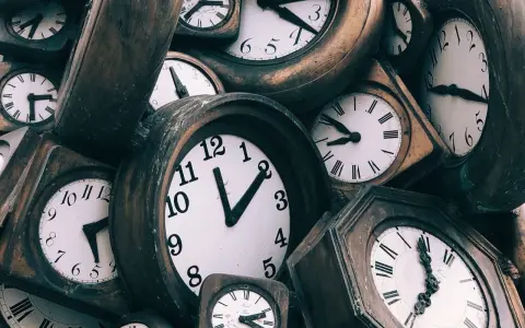 Stos starych zegarów, niektóre z rzymskimi cyframi, inne z arabskimi.