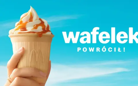 Lody McDonald's w wafelku z polewą karmelową, trzymane w dłoni na tle błękitnego nieba.