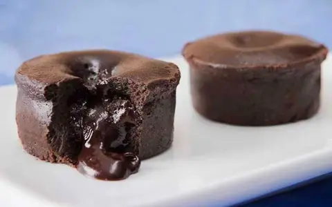 Fondant au chocolat coulant, une gourmandise inspirée de la recette de Cyril Lignac. Le cœur liquide de chocolat fond sur la plaque blanche.