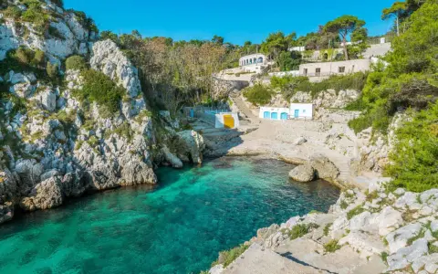 Baia incantevole con acque cristalline, perfetta per un itinerario Puglia 3 giorni. Case bianche e rocce a picco sul mare.