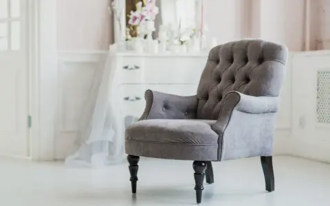 Elegante sillón gris con botones, ideal para un tocador. ¿Cuánto vale tapizar una silla así?