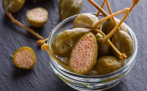 Cucunci sotto sale in una ciotola di vetro, alcuni tagliati a metà rivelano la loro polpa interna.