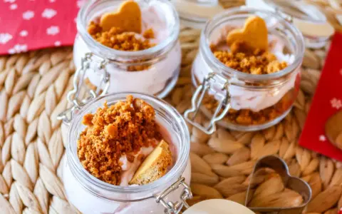 Söta små glasburkar med rosa kräm, smulad kaka och hjärtformade kex. Ett perfekt mjukglass recept utan glassmaskin för alla hjärtans dag.