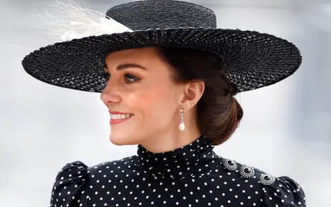 Księżna Kate w eleganckiej, czarno-białej sukience w grochy i stylowym kapeluszu.