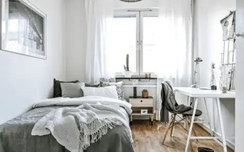 Chambre 10m2 lumineuse avec lit confortable, bureau et fenêtre. Un cactus sur le rebord de fenêtre ajoute une touche de verdure.
