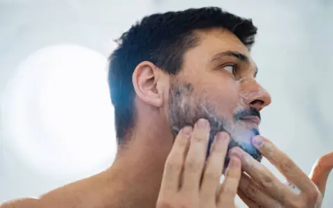 Hombre aplicándose espuma para quitarse la barba.