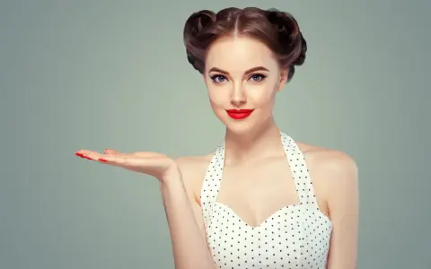 Kobieta w stylu pin-up z burzą loków i czerwoną szminką prezentuje dłoń.