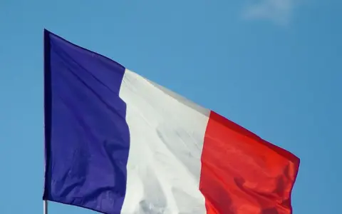 La bandera de Francia ondea con orgullo contra un cielo azul claro.