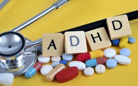 Stetoskop i tabletki, kapsułki oraz literki tworzące napis ADHD. Leki na ADHD to temat obrazu.
