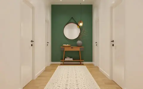 Un couloir moderne avec un mur vert, un miroir rond, une console en bois et un tapis. Une belle idée déco couloir moderne.