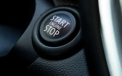Nahaufnahme eines Start/Stop-Knopfes im Auto. Der Knopf ist beleuchtet und zeigt die Worte "START ENGINE STOP".