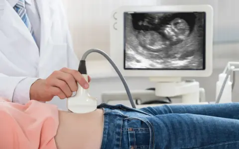 Lekarz wykonuje USG. Na ekranie widać zarodek, to 11 tydzień ciąży, który to miesiąc rozwoju dziecka.