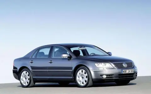 Elegancki, ciemnoszary VW Phaeton W12 z lat 2002-2006 prezentuje się na tle błękitnego nieba.
