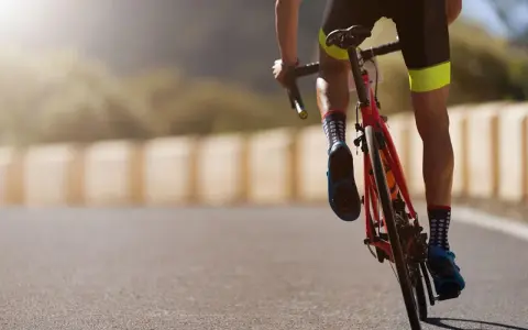 Cyclist in neon-accented shorts and polka-dot socks powering up a hill, embodying a dedicated sprint workout plan.
