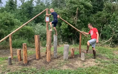 Junge und Mann balancieren auf Baumstämmen im Kletterpark Plau am See.