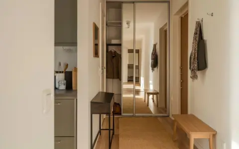 En ljus hall med spegelskjutdörrar, en smal konsol, en träbänk och en matta. Perfekt hall inspiration för en funktionell och stilren entré.