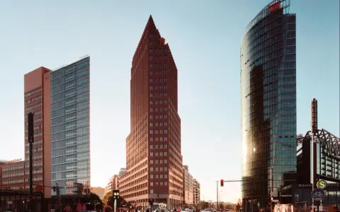 Moderne Hochhäuser am Potsdamer Platz in Berlin, darunter der spitze roter Backsteinbau, der an den schnellsten Fahrstuhl Berlins erinnert.