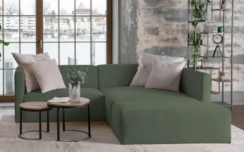 Divani verdi in colori di tendenza, con cuscini chiari e tavolini rotondi. Un angolo relax moderno con vista sul lago.