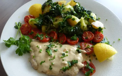 Escalope de veau crémeuse, accompagnée de pommes de terre sautées, tomates cerises rôties et quartiers de citron.