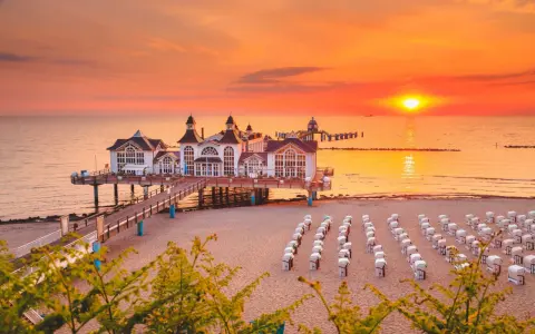 Zachód słońca nad molo w Sellin, na Rugii, największej wyspie Niemiec. Puste kosze plażowe czekają na gości.