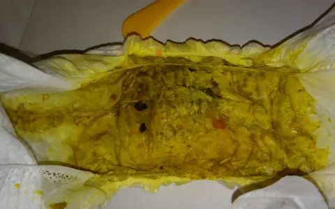 Żółta, luźna kupka w pieluszce, z widocznymi grudkami i kilkoma czerwonymi kropkami.
