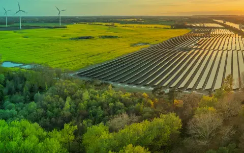 Weite Landschaft mit Windrädern, Solarpanels und grünen Feldern. Ein Zeichen für gesellschaftliche Akzeptanz erneuerbarer Energien.