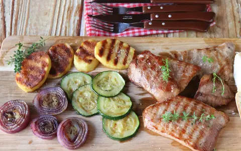 Delicioso escalope de ternera a la parrilla con patatas, calabacín y cebolla morada.