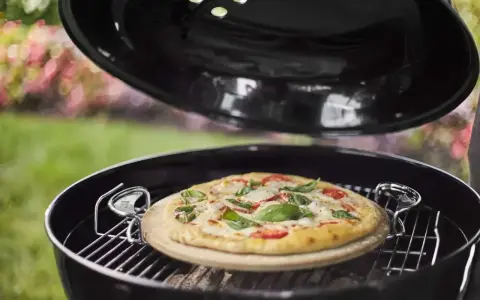 Pizza na kamieniu w grillu, gotowa do podania. Po pieczeniu czyszczenie kamienia do pizzy jest proste.