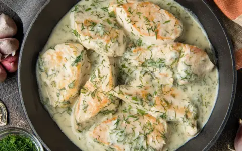 Pyszny kurczak w sosie śmietanowym z koperkiem, podany w żeliwnej patelni. Aromatyczny i kremowy.