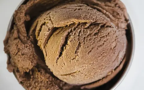 Une généreuse boule de glace au chocolat, crémeuse et givrée, dans un bol métallique.