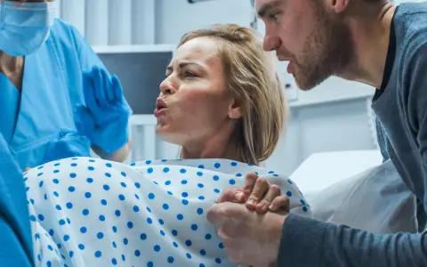 Kobieta rodzi, wspierana przez partnera i położną. W tej chwili kluczowa jest oksytocyna, hormon miłości i porodu.