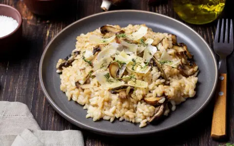 Kremowe risotto z pieczarkami, posypane parmezanem i ziołami.