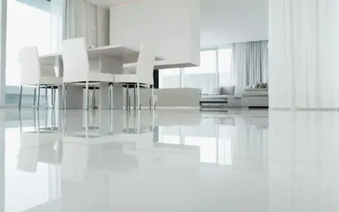 Un moderno salón con un impecable suelo resina epoxi vivienda, reflejando la luz y el mobiliario minimalista.