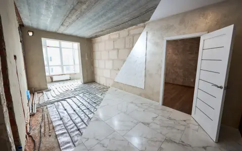 Habitación en construcción con suelo de mármol y sistema de calefacción por suelo radiante. El alicatado que es, se ve en el suelo y en la pared.