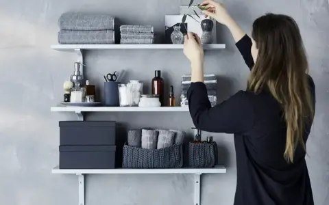 Idee mensole ingresso: organizzazione bagno con asciugamani grigi, scatole e cestini in maglia.