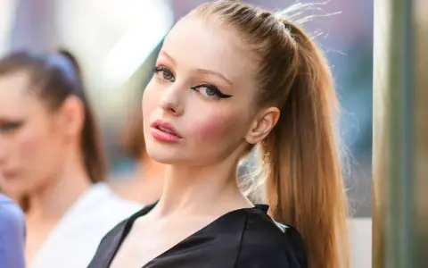 Modelo con delineado cat eye dramático y labios rosados, su cabello recogido en una coleta alta.