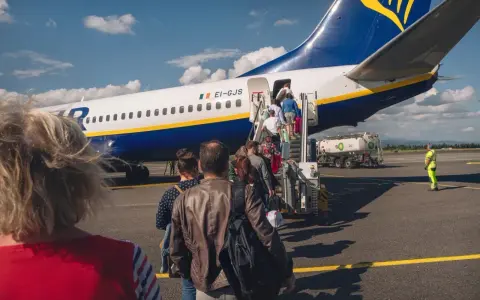 Pasażerowie wsiadają do samolotu Ryanair. Zastanawiasz się, ile kosztuje odprawa na lotnisku? Tutaj nie ma dodatkowych opłat.