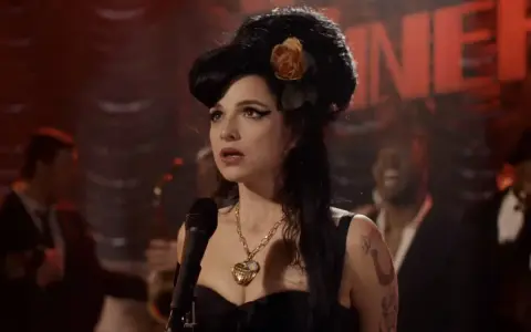 Aktorka wcielająca się w Amy Winehouse na scenie, w charakterystycznej fryzurze i z naszyjnikiem. Scena przypomina fragmenty z filmów o jej życiu.
