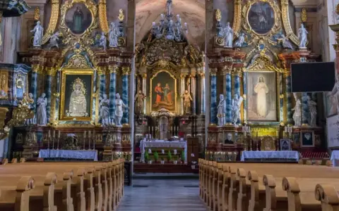 Bogato zdobione wnętrze kościoła, prawdopodobnie należącego do zakonu jezuitów, z ołtarzem głównym, obrazami i rzeźbami.