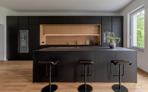 Elegantes cocinas negras y madera, con isla central y taburetes modernos.