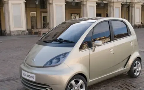 Złoty Tata Nano na brukowanym placu przed zabytkową kamienicą.