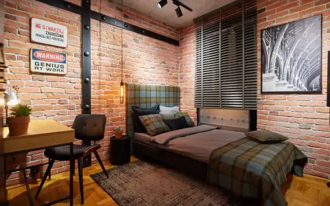Aranżacje pokoju młodego mężczyzny w stylu loft. Czerwona cegła, metalowe belki i stylowe dodatki tworzą niepowtarzalny klimat.