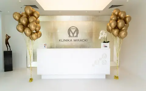 Recepcja kliniki z bukietami złotych balonów i rzeźbą.
