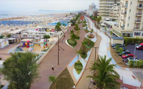 Passeggiata lungomare a Rimini Miramare con aree gioco, stabilimenti balneari e palazzi affacciati sul mare.