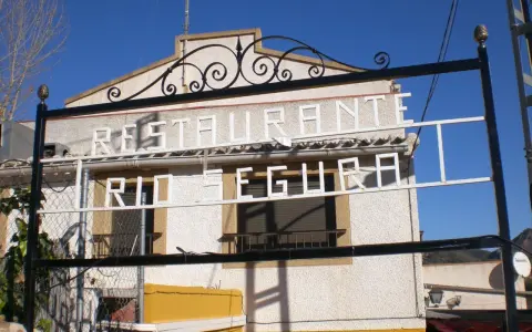 Restaurante El Gallego Elche de la Sierra, con letrero "Restaurante Río Segura" en blanco sobre fachada texturizada.